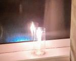 candle in a glass sat next to a window