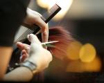 hands holding ends of brunette hair and a pair of hairdressing scissors