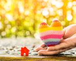 Hand facing palm up holding a multi-coloured knitted heart