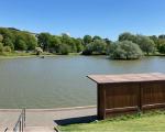 A lake in Portishead surrounded by trees under a clear blue sky