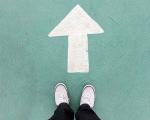 someone stood next to a white arrow on the floor pointing away from them