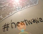 seawater lapping on a beach with the word' heatwave' written into the sand