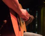 person sat down in a dark room playing guitar
