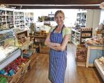 woman wearing an apron stood with her arms crossed in her shop