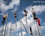 People stood at the top of poles with the sky behind them