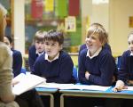 school children sat in class talking to their teacher