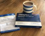 lateral flow tests on a wooden table with a mug of coffee