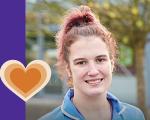 carer smiling towards the camera. Her hair is pulled up into a ponytail.