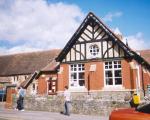 front of a Victorian school building against a cloudy blue sky