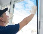 man fitting a pane of glass into a into a window frame