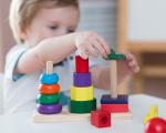 toddler stacking colour wooden blocks on a table