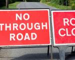 two road closed signs in the middle of a road