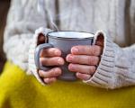 a steaming mug of tea being held in a lady's hands