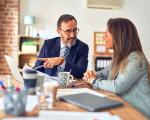 Man and a woman in office wear sat at a table having a conversation