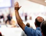 A man putting his hand up to speak at an event