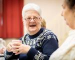 an older lady smiling with a cup of tea