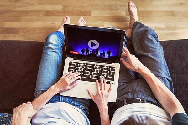 a couple sat on a sofa with a laptop watching YouTube