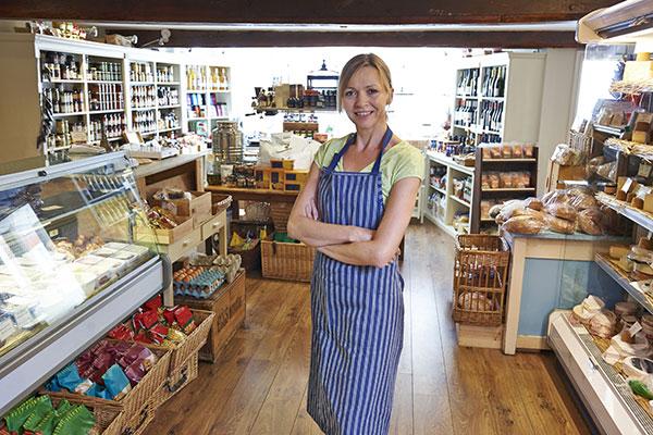 woman wearing an apron stood with her arms crossed in her shop