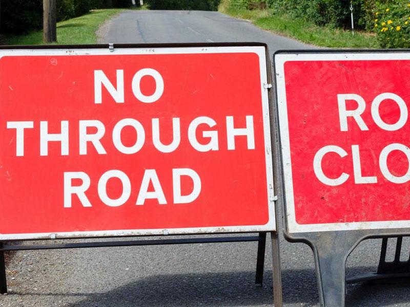 two road closed signs in the middle of a road
