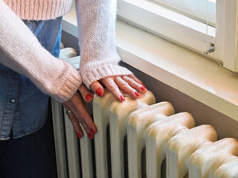 person placing their hands on top of a radiator