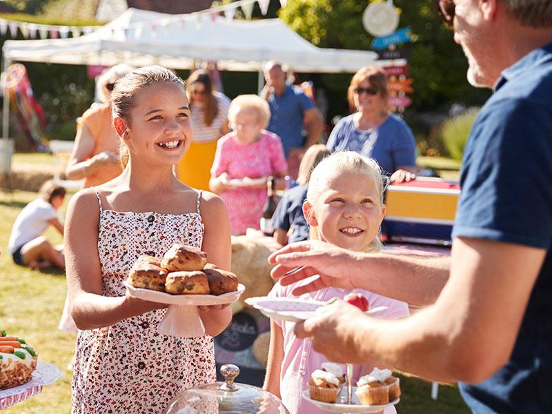 A girl buying cake at an outdoor festival