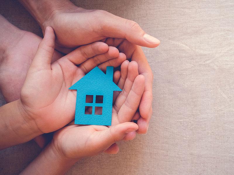 stock shot of hands holding a cut-out house