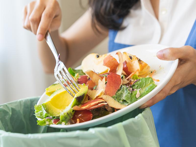 Someone putting food waste in a caddy