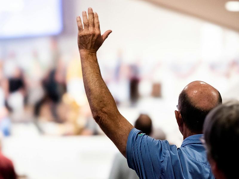 A man putting his hand up to speak at an event