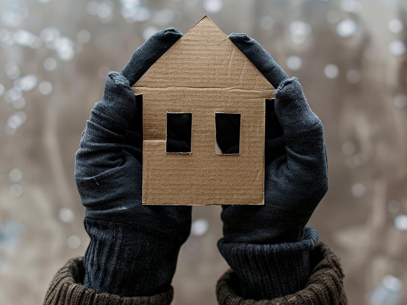 Hands holding a cardboard cutout of a home