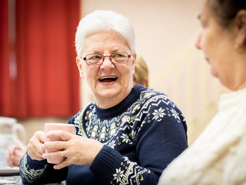 an older lady smiling with a cup of tea