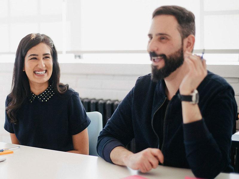 a man and a woman smiling and talking in a meeting room