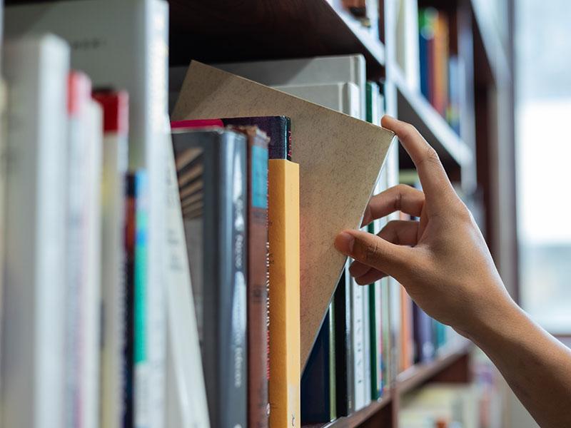 This image shows a person with books in a library