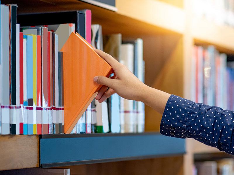This shows someone picking a book in a library