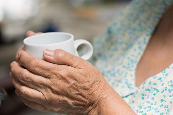 hands of an older person holding a mug