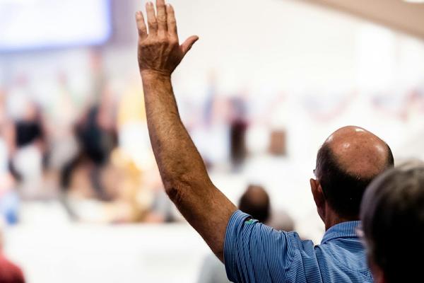 A man putting his hand up to speak at an event