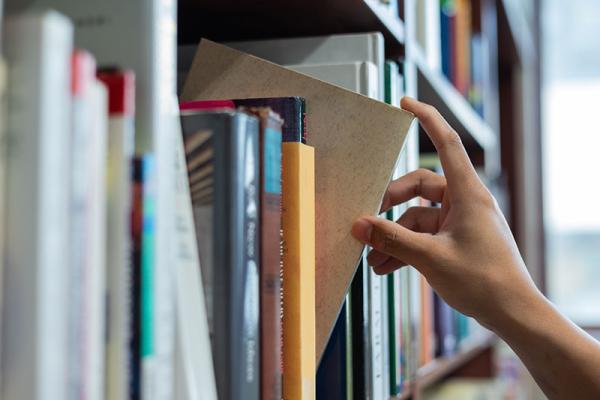 This image shows a person with books in a library