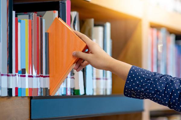 This shows someone picking a book in a library