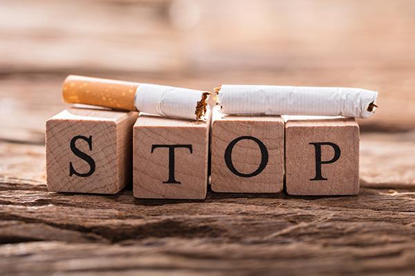 broken cigarette on top of letter blocks that spell 'stop'